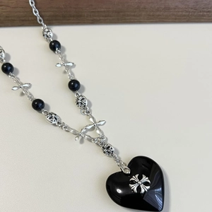 Detail of gothic black heart pendant with silver cross elements and beaded chain design
