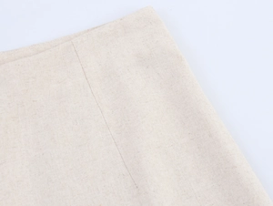 Detailed macro view of beige faux linen fabric texture and stitching on the sleeveless vest