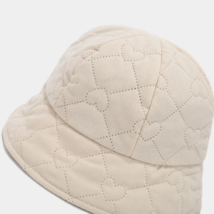 Detail of cream white bucket hat with intricate heart quilted embroidery patterns