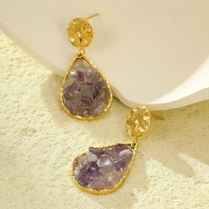 Golden teardrop earrings with purple natural stones on a textured minimalist background