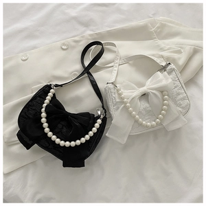 Detail of elegant handbags featuring oversized bows and pearl handles in black and white
