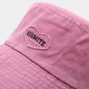 Close-up of pink washed cotton bucket hat with heart embroidery and fringe details