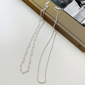 Detail of 925 sterling silver paperclip and shimmering chain necklaces on vintage books
