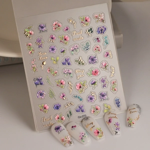 Macro view of floral nail stickers with gold foil lettering and 3D flower designs