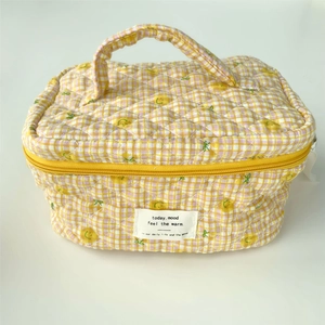 Detail of yellow checkered quilted cotton vanity bag with handle and chic text label