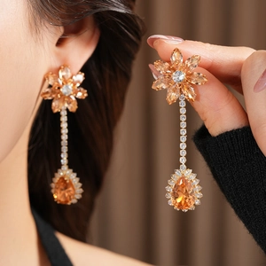 Close-up of elegant flower dangle earrings with champagne zircons worn by a model