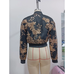 Vista posteriore di una giacca corta nera con intricato ricamo floreale in paillettes dorate