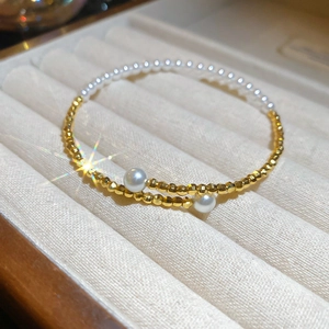Detail of double-layer bracelet with gold beads and white pearls in a beige velvet box