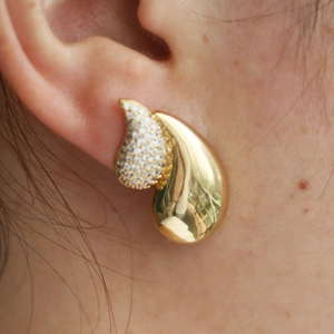 Close-up of heart-shaped gold earring with cubic zirconia droplets on ear lobe
