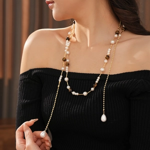 Detail of vintage style long pearl necklace with tiger eye beads and golden chains