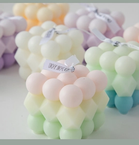 Detailed view of pastel macaron cube bubble candles with silk ribbons for home decor