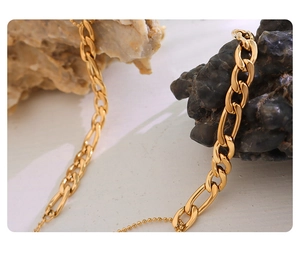 Macro shot of gold-plated Figaro chain links on a natural stone surface for 18K jewelry