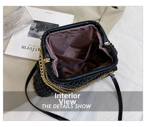 Detail view of the black pleated clutch bag interior with gold hinges and brown lining