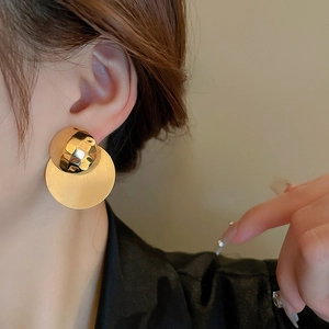 Primo piano di modella con orecchini geometrici dorati dalla superficie martellata