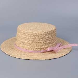 Detailed side view of a natural raffia straw boater hat featuring a pink bow