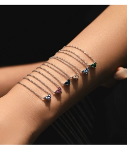 Detailed view of silver heart necklaces with various colored gemstones on model arm