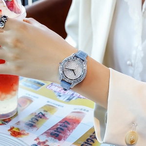 Close-up of luxury women watch with full diamond bezel and light blue leather strap