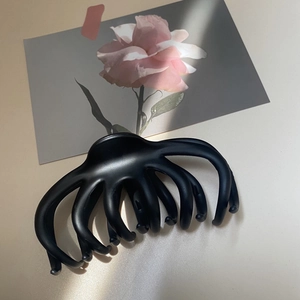 Close-up of a large black matte hair claw clip with elegant curved hollow design
