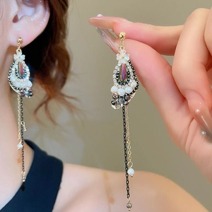 Macro shot of long gold tassel earrings with painted flowers and iridescent beads