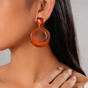 Gros plan d'une boucle d'oreille géométrique en résine ambrée sur un mannequin
