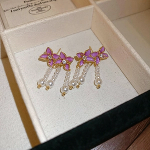 Detail of purple enamel flower earrings with cascading white pearl tassels on jewelry box