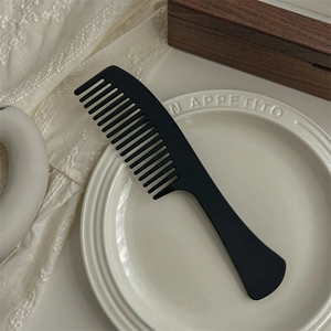 Detail of wide tooth black acetate hair comb on decorative plate for curly hair styling
