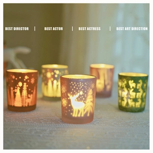 Close-up of frosted glass candle holders with reindeer and snowflake embossed patterns