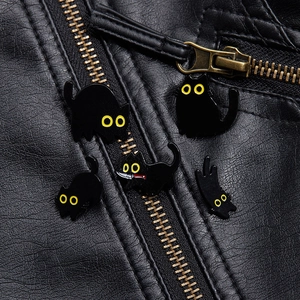 Vista detallada de pines de esmalte de gato negro en una elegante chaqueta de cuero negro