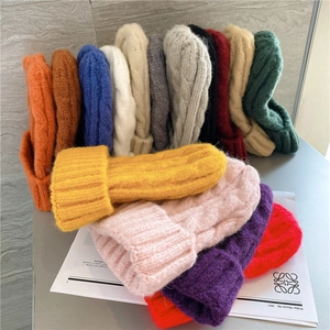 Stack of chunky cable knit beanies in multiple vibrant colors for autumn and winter warmth