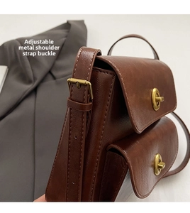 Detail of adjustable shoulder strap with antique bronze buckle on brown vintage leather bag