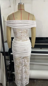 Detail of white lace off-shoulder dress featuring floral embroidery and ruching design