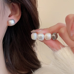 Macro shot of square pearl earrings in white, cream, and grey with a soft pearlescent luster