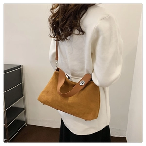 Gros plan d'un sac bandoulière en daim marron avec fermoir tournant et anses en cuir
