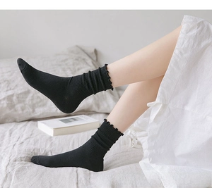 Close-up of black mid-calf socks with ruffle trim and vertical ribbed knit texture