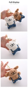 Detail of plush animal keychains with denim overalls and gold metal clasp hooks