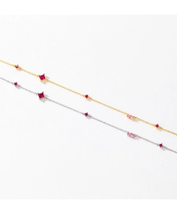 Dettaglio di bracciali in argento e oro con gemme rosse e rosa su sfondo bianco
