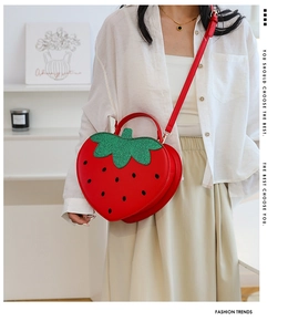 Detail of strawberry shaped crossbody bag with glitter green leaves and red seeds