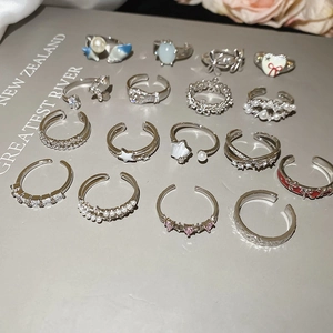 Close-up of 15 silver-colored rings with stars, pearls and zircons on grey book