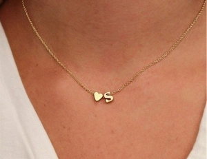Gros plan du collier doré avec pendentifs cœur et lettre S sur le cou d'un modèle