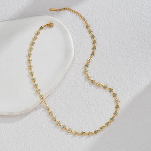 Macro shot of gold stainless steel necklace featuring small blue flower charm details