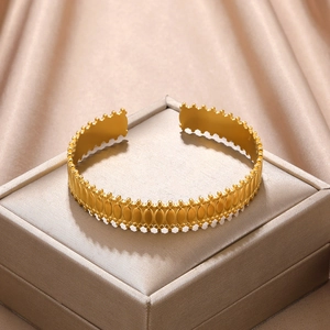 Detailed macro view of golden cutout geometric cuff bracelet on champagne silk