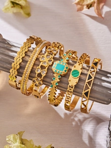 Close-up of vintage gold bangle collection with geometric patterns and zircon inlay