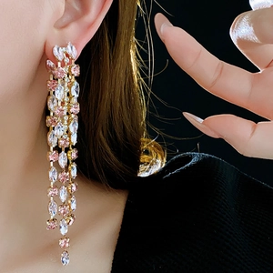Detail of pink crystal tassel earrings with gold-tone finish on model with black background