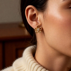 Detail of elegant hollow flower stud earring with zircon stone worn by a model