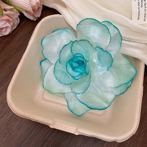 Detail showing layers of light blue mesh fabric flower hair clip with soft gradient petals