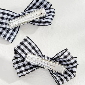 Detail of two black and white checkerboard fabric bow hair clips with silver metal duckbill clips