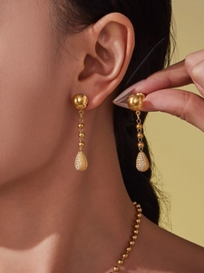 Gros plan de boucles d'oreilles dorées avec zircon scintillant sur un modèle
