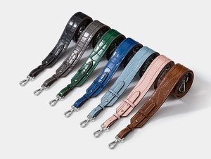 Detail showing various colors of crocodile pattern leather shoulder straps with metal hooks