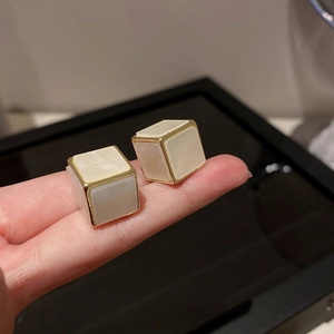 Gros plan de boucles d'oreilles cubes avec incrustation blanc laiteux et cadre doré