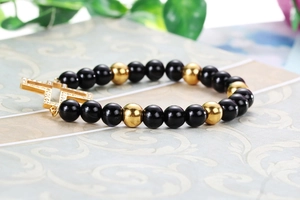 Detailed macro view of black beads and gold cross pendant on elastic bracelet